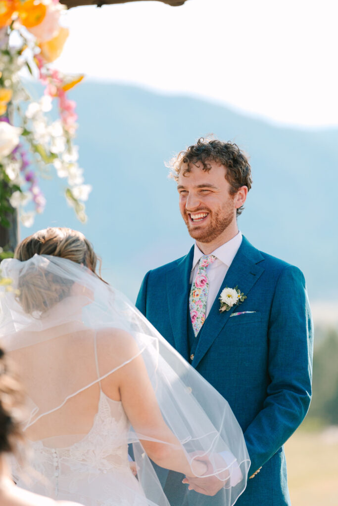 Groom smiling at the bride while exchanging vows at spruce mountain ranch