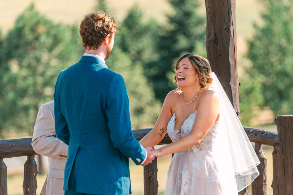 bride and groom laughing candidly during their ceremony at spruce mountain ranch