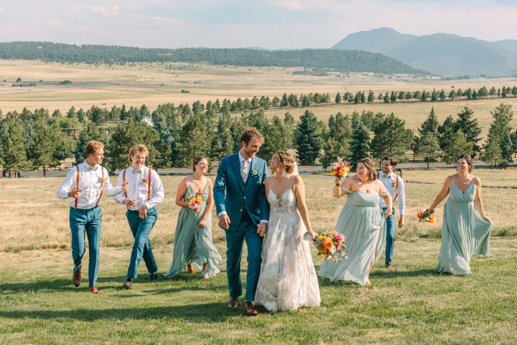 Colorful wedding party walking and laughing with bride and groom at spruce mountain ranch