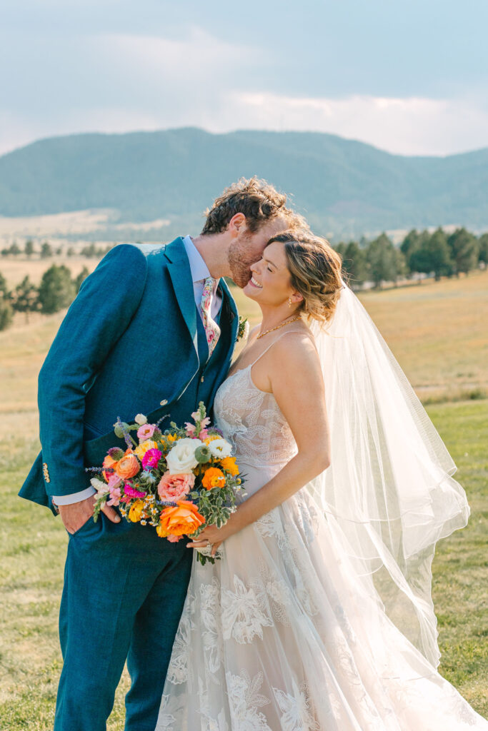 Groom kissing bride on the cheek at spruce mountain rancgh