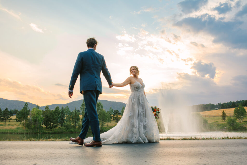 Bride and groom walking past each other grabbing hands at spruce mountain ranch